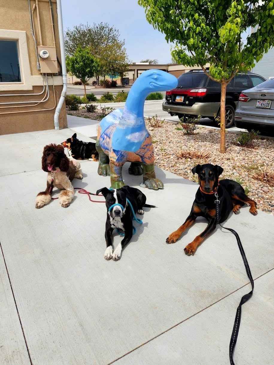 Dogs in training posed by a dinosaur statue in Vernal, Utah